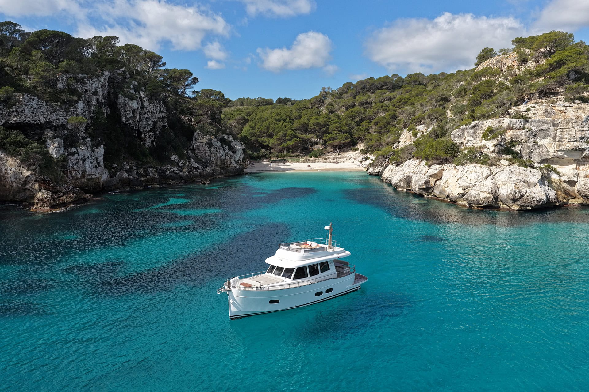 ista aérea de un Menorquín 48 FB fondeado en una cala de aguas cristalinas en Menorca