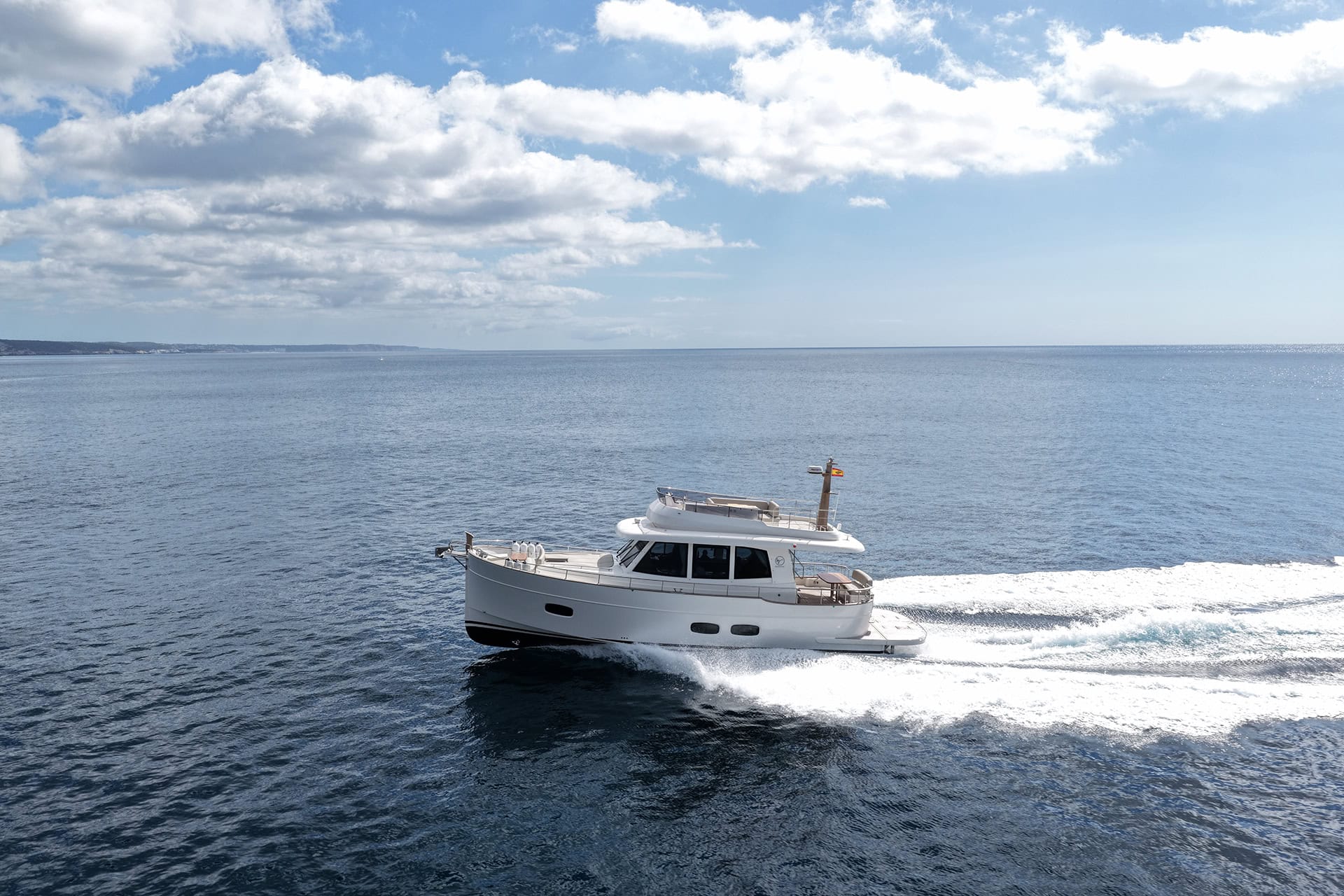 Vista lateral de un Menorquín 48 FB navegando a velocidad de crucero frente a la costa de Menorca