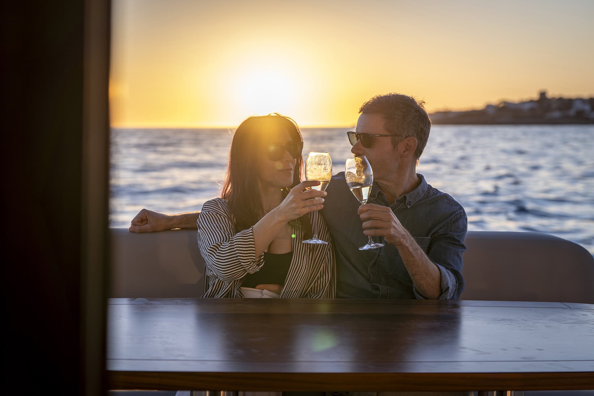 Pareja brindando con champagne al atardecer a bordo de un Menorquín 48 FB