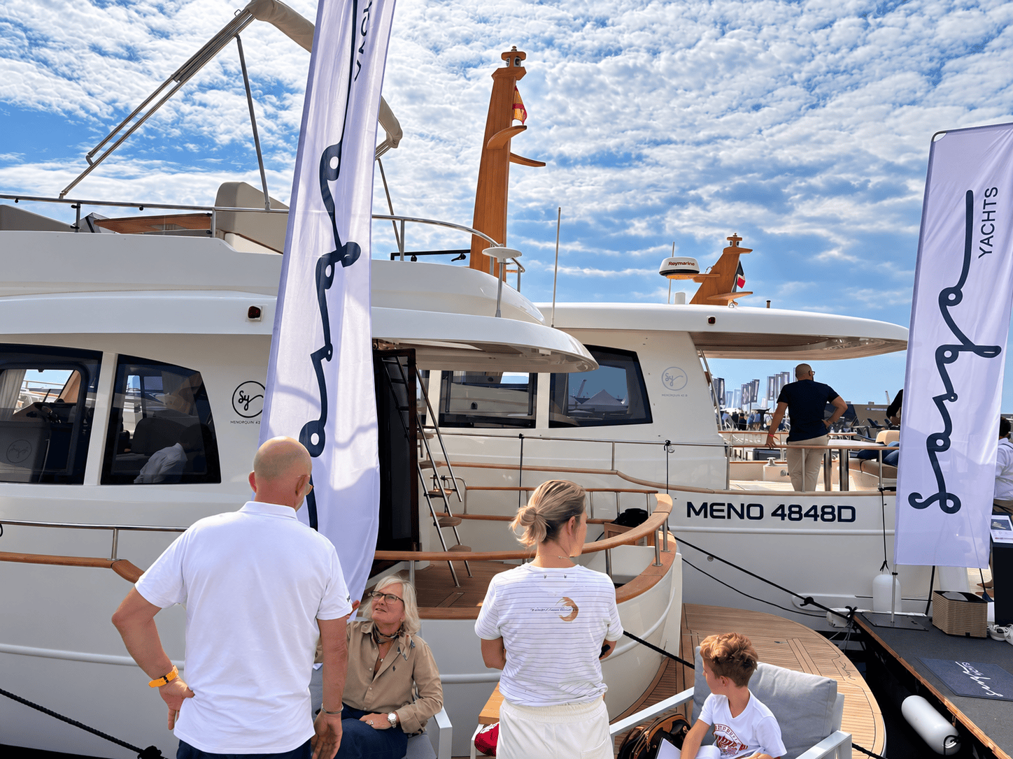 Menorquín 42 FB con flybridge junto a un Menorquín 48 HT, con visitantes y banderas de Sasga en el pantalán.